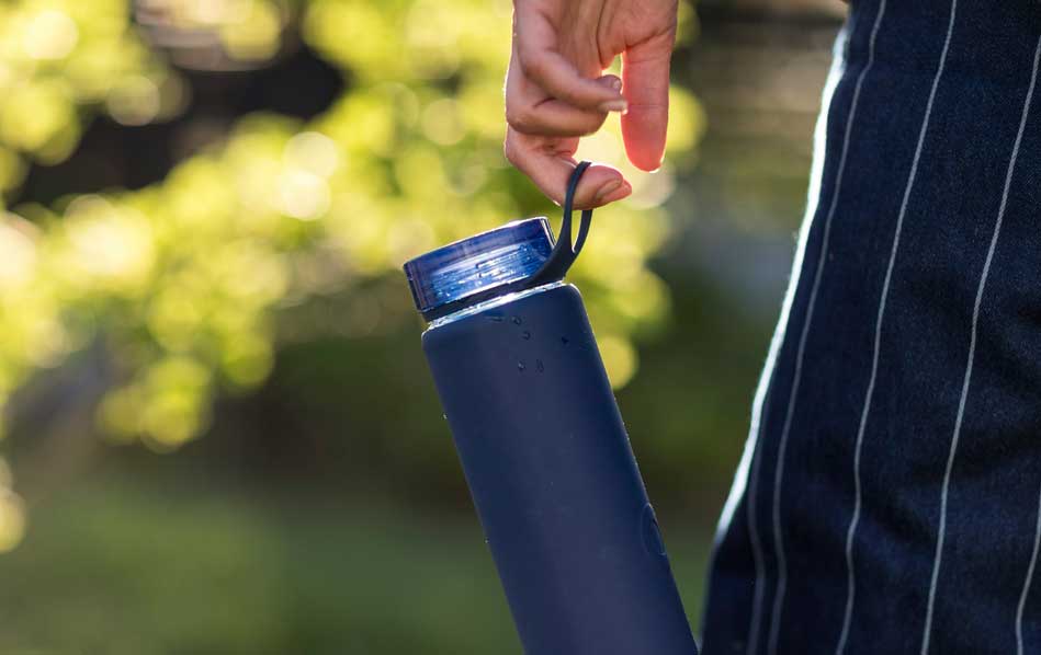 Person holding a blue water bottle with an open cap.